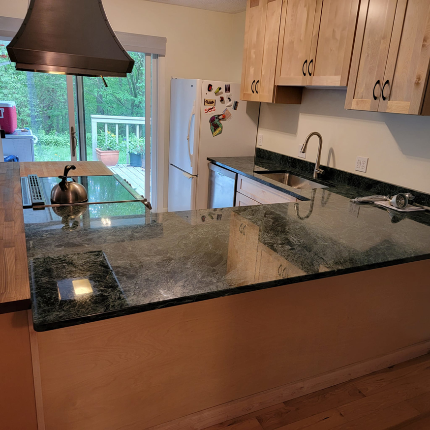 A newly renovated kitchen featuring dark green granite countertops and light wood cabinets by Jonny Hinton - Handyman Extraordinaire in Colorado Springs, CO.
