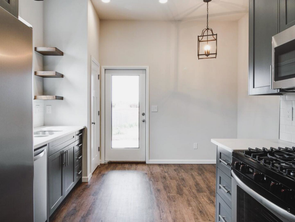 A modern kitchen and dining area with new cabinets, range, and a stylish pendant light by Power Roofing & Construction in Norman, OK.