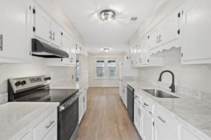 A newly renovated kitchen with white cabinets and new appliances by All Pro Roofing and Renovations in Sachse, TX.