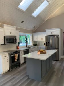 A renovated kitchen featuring white cabinets, a gray island, and new flooring by Coastal Surface Design in Virginia Beach, VA.