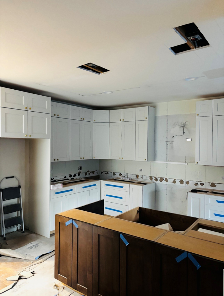 A kitchen renovation project with new white cabinets installed, showing ongoing construction by All In Service Group, LLC in Chicago, IL.