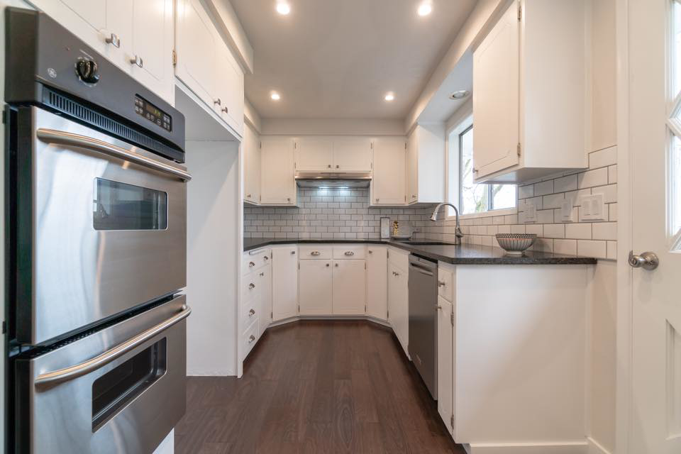 A modern kitchen renovation with white cabinets, subway tile backsplash, and stainless steel appliances by R2S Build in Eugene, OR.