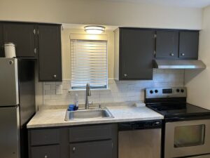 A renovated kitchen featuring dark gray cabinets, new countertops, and subway tile backsplash by Brothers Home Improvement in East Hartford, CT