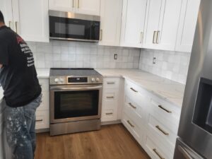 Kitchen renovation featuring new white cabinets, countertops, and backsplash by Gladiator Flooring LLC in Summerville, SC.