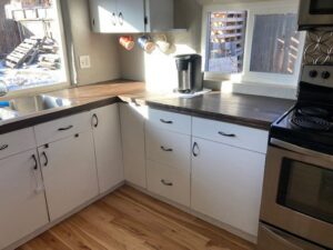 A completed kitchen renovation featuring new countertops, white cabinets, and flooring by Rod's Handyman Services, LLC in Boise, ID.