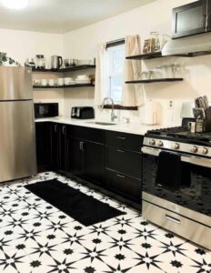 A stylish kitchen renovation featuring black cabinets, a unique patterned floor, and stainless steel appliances by The Sioux Falls Handyman in Sioux Falls, SD.