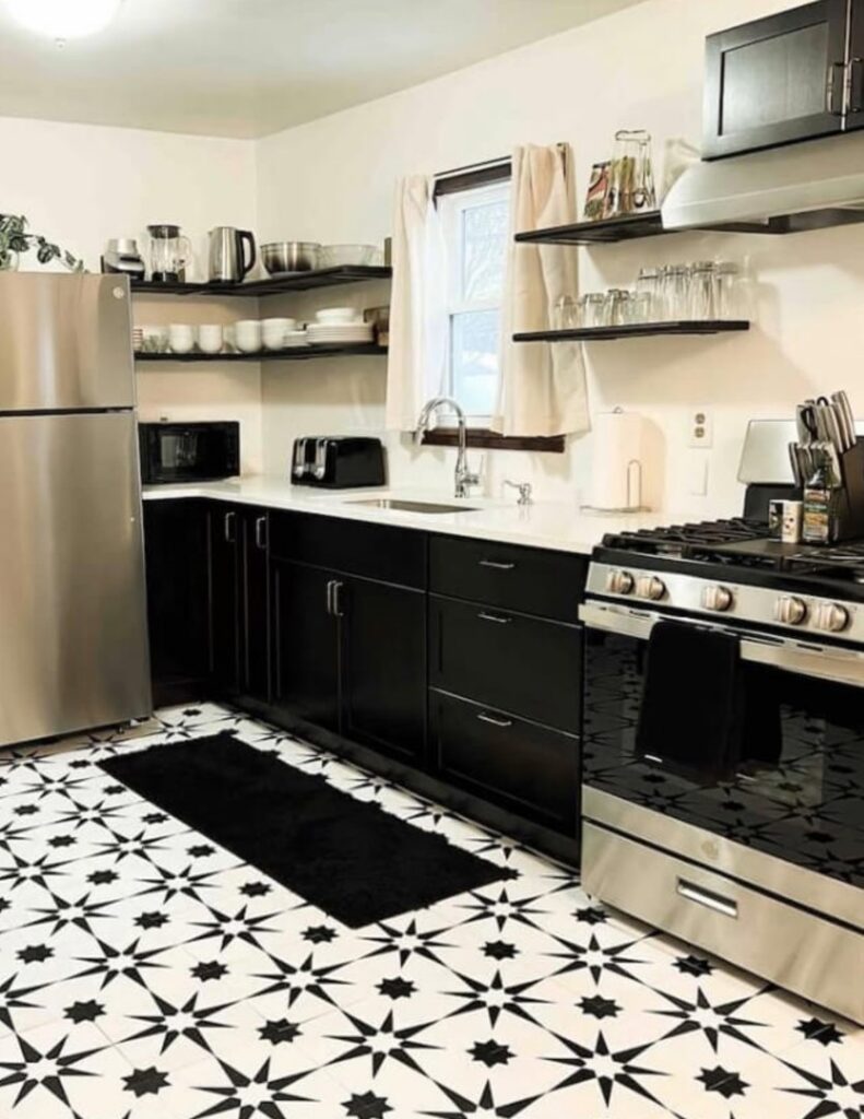 A stylish kitchen renovation featuring black cabinets, a unique patterned floor, and stainless steel appliances by The Sioux Falls Handyman in Sioux Falls, SD.