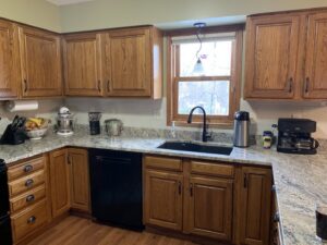 A kitchen renovation with wooden cabinets, granite countertops, and a white subway tile backsplash by Surfaces By Design in Duluth, MN.