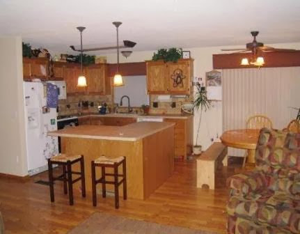 Renovated kitchen with wooden cabinets, a central island, and dining area by Tschida Construction in Cologne, MN.