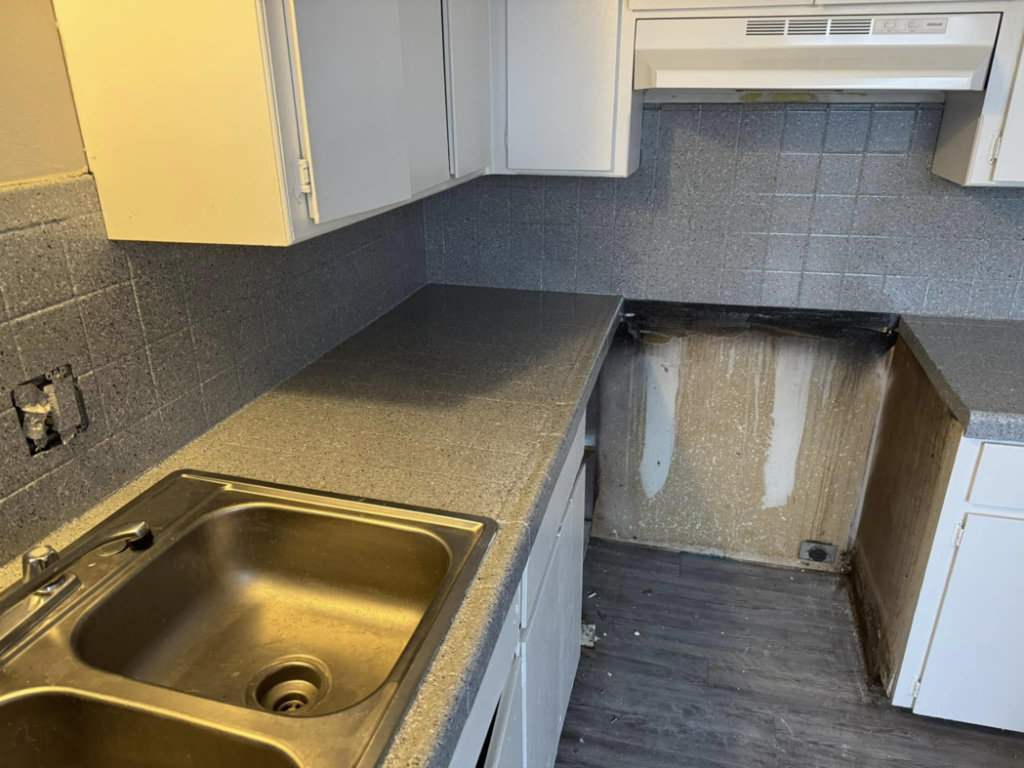 A kitchen area showing a grey speckled countertop and exposed wall during resurfacing by That Resurfacing Guy LLC in Oklahoma City, OK.