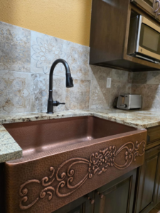 A detailed view of a new copper kitchen sink and decorative tile backsplash by A&R Home Improvements in El Paso, TX
