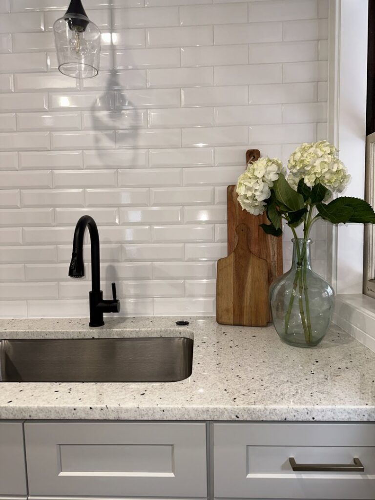 A close-up of a kitchen sink area with a white subway tile backsplash, expertly installed by Westrick Homes in St. Louis, MO.