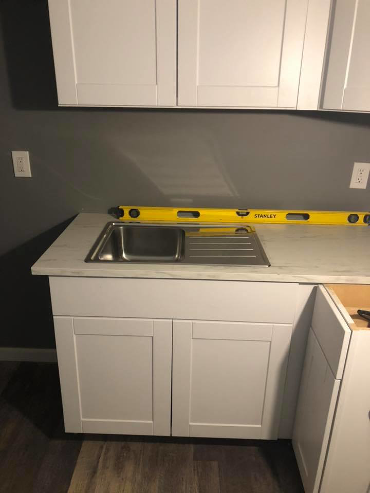 Kitchen sink and cabinet installation in progress, ensuring level surfaces by Executive Property Construction at 301 Maple Blvd.