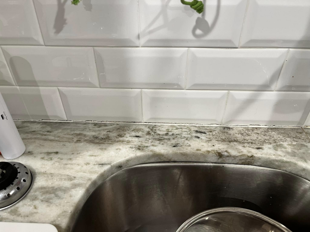 Before image showing old, discolored caulk around a kitchen sink, ready for repair by PODavis Home Helpers in Little Rock, AR