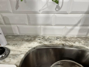 Before image showing old, discolored caulk around a kitchen sink, ready for repair by PODavis Home Helpers in Little Rock, AR