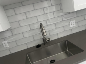 Newly installed kitchen sink, modern faucet, and subway tile backsplash by Fox Solutions Corp in Worcester, MA