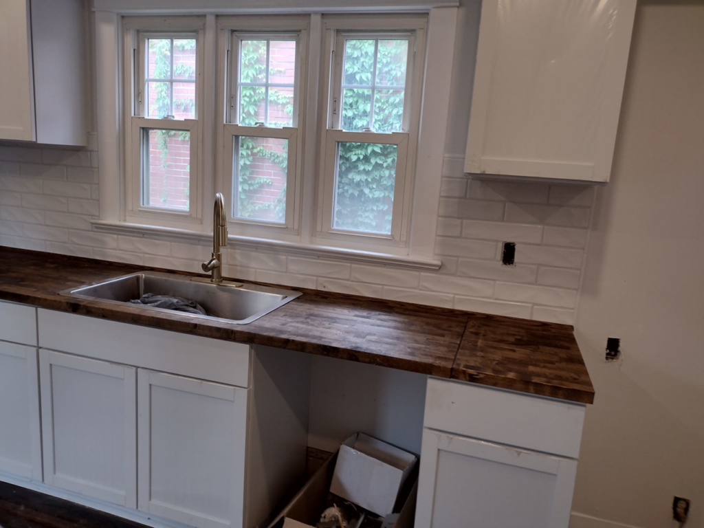 Kitchen sink installation with wooden countertops and white cabinets by I.B. Remodeling LLC in Dayton, OH.