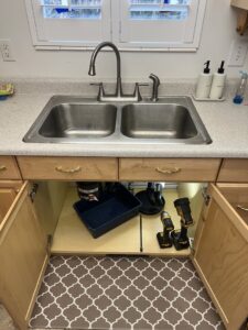 Kitchen sink cabinet with tools, indicating plumbing repair or cabinet work by Titan Handyman Services in Lewes, DE