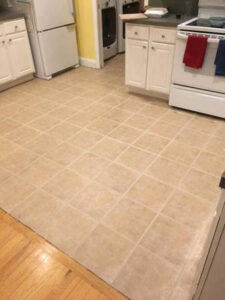 A kitchen floor with neatly installed square tiles by True Alchemy - Tile & Grout Restoration in Denver, CO.