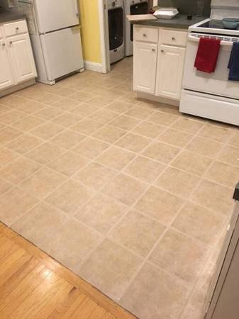 A kitchen floor with neatly installed square tiles by True Alchemy - Tile & Grout Restoration in Denver, CO.