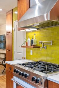 A kitchen stove with a yellow tile backsplash and a convenient pot filler faucet, installed by Integrated Contracting and Renovations in Pittsburgh, PA.
