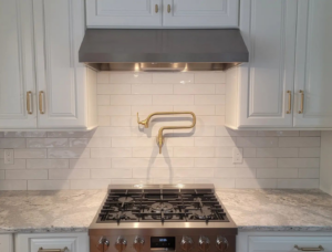 Kitchen stove, pot filler faucet, and range hood installation by Walker Kitchen Design in Granby, CT.