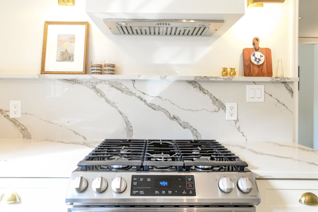 A kitchen stovetop area with a white marble-patterned backsplash and countertop installed by Counter Fitters in Savannah, GA