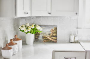 A detailed view of a kitchen with a decorative tile backsplash and clean countertop by ADAMS Pro Finish in Spring Hill, TN.