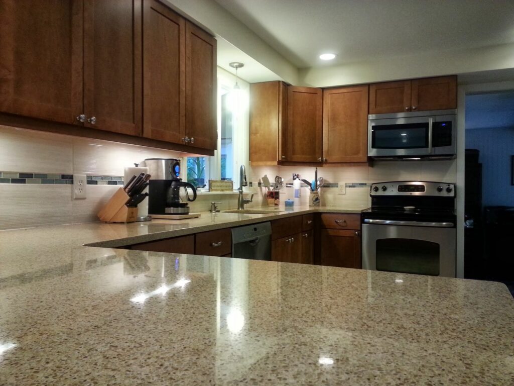 A kitchen update featuring light granite countertops, dark wood cabinets, and a tiled backsplash by Mainville Construction & Remodeling LLC in Newington, CT.