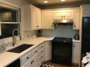 A kitchen update featuring white cabinets, new countertops, and a decorative patterned backsplash by Boisen Remodeling LLC in Appleton, WI.
