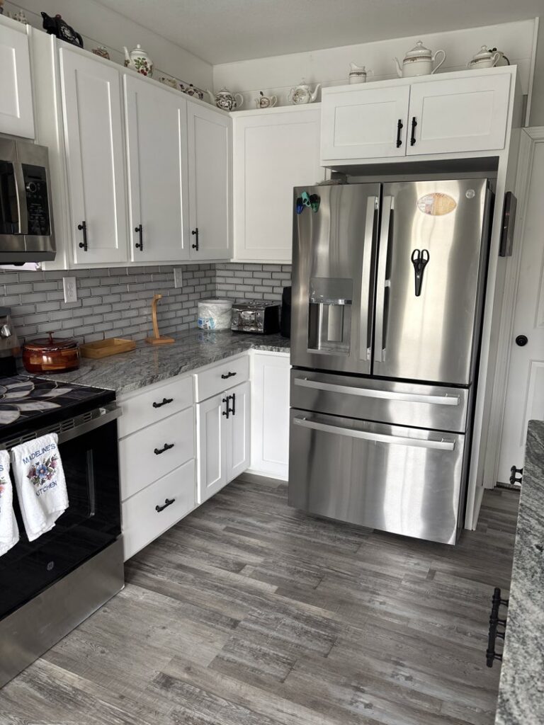 An upgraded kitchen showcasing white cabinets, stainless steel appliances, and granite countertops by KB Home Repairs & Improvements, LLC in Shawnee, KS.