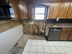 Kitchen wall demolition showing exposed plumbing and insulation by JM Renovations LLC in Moore, OK.