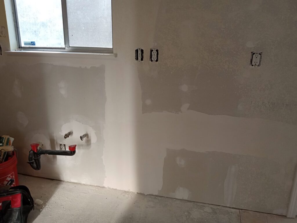Kitchen wall with new drywall, electrical outlets, and plumbing rough-in by Cal Heights Construction And Handyman Services in Bakersfield, CA