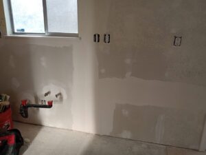 Kitchen wall with new drywall, electrical outlets, and plumbing rough-in by Cal Heights Construction And Handyman Services in Bakersfield, CA