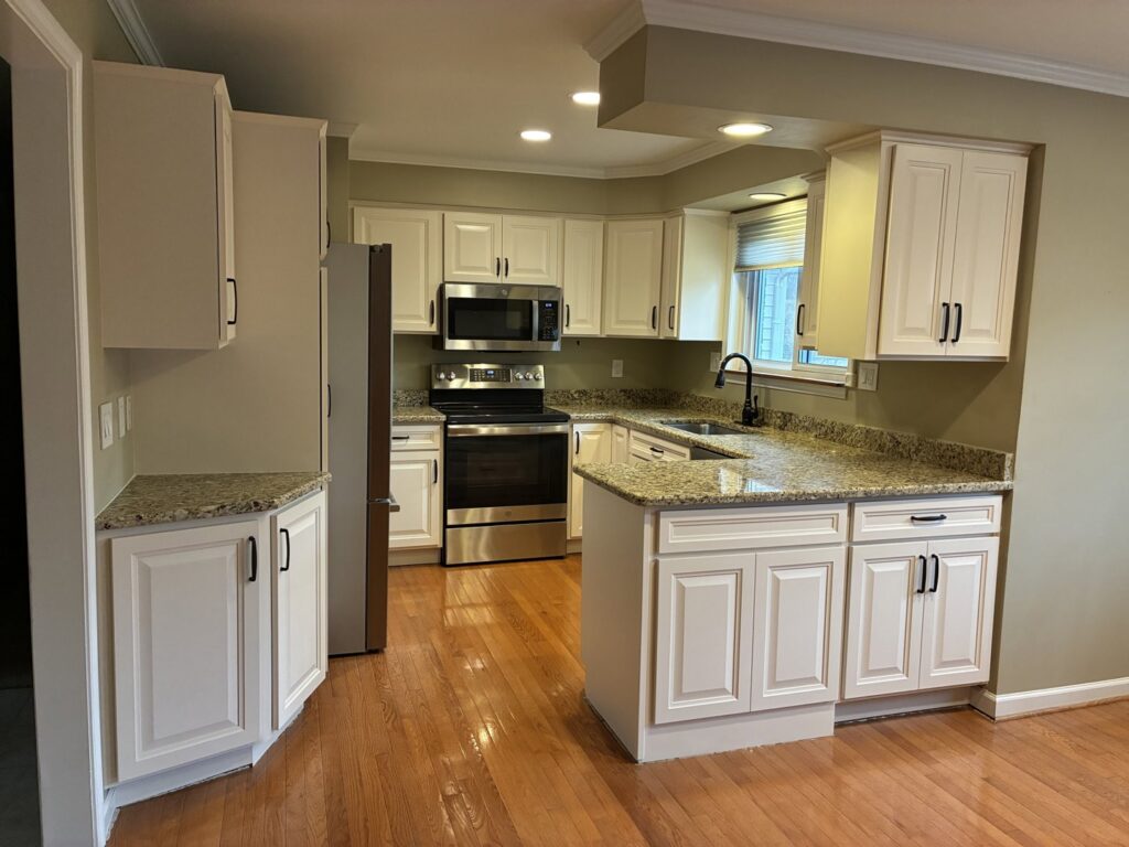 A renovated kitchen with white cabinets, granite countertops, and stainless steel appliances by Creative Building & Remodeling in Warren, MI
