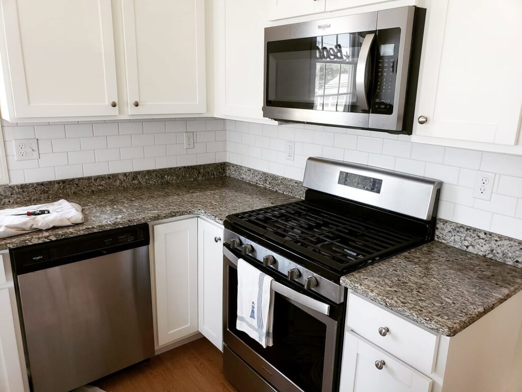 Kitchen remodel with white cabinets, granite countertops, subway tile backsplash, and stainless steel appliances by Supreme Tile & Flooring in Charlotte, NC.