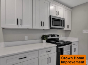 A renovated kitchen featuring white cabinets, quartz countertops, and new microwave and range installed by Crown Home Improvements in Charlotte, NC