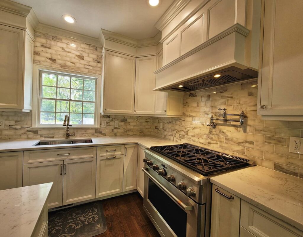 Renovated kitchen with white cabinets, light tile backsplash, a gas range, and a pot filler by Supreme Tile & Flooring in Charlotte, NC.