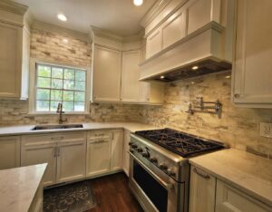 Renovated kitchen with white cabinets, light tile backsplash, a gas range, and a pot filler by Supreme Tile & Flooring in Charlotte, NC.