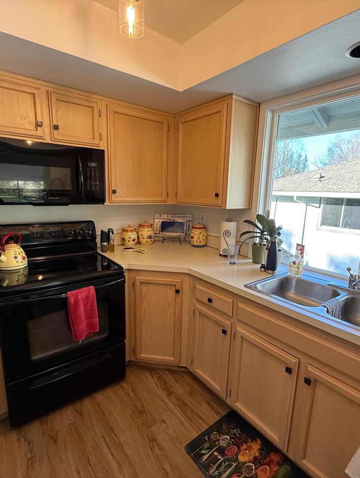 Kitchen with light wood cabinets and black appliances before renovation by Cabinet Refinishing Northwest in Beaverton, OR.