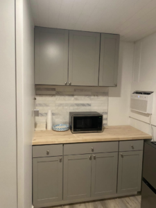 A renovated kitchenette featuring new grey cabinets, wooden countertop, and tiled backsplash by Atlanta Handyman and Repair LLC in Johns Creek, GA.