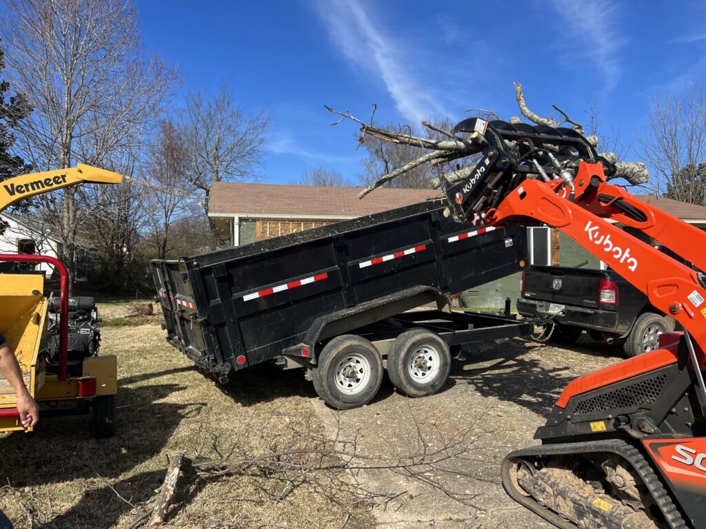 A Kubota compact track loader loading tree branches into a dump trailer for Liberty Tree in Fort Smith, AR.