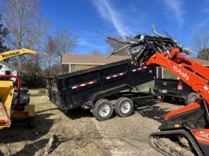 A Kubota compact track loader loading tree branches into a dump trailer for Liberty Tree in Fort Smith, AR.