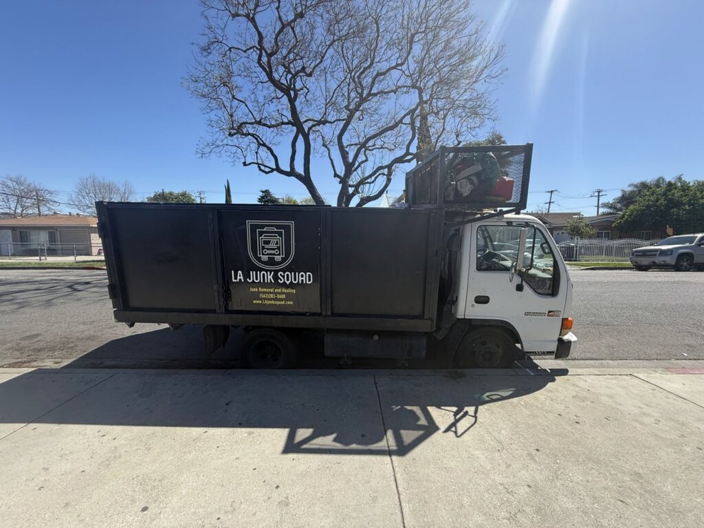An L.A. Junk Squad truck loaded with junk, parked on a residential street in Bell Gardens, CA, ready for disposal.