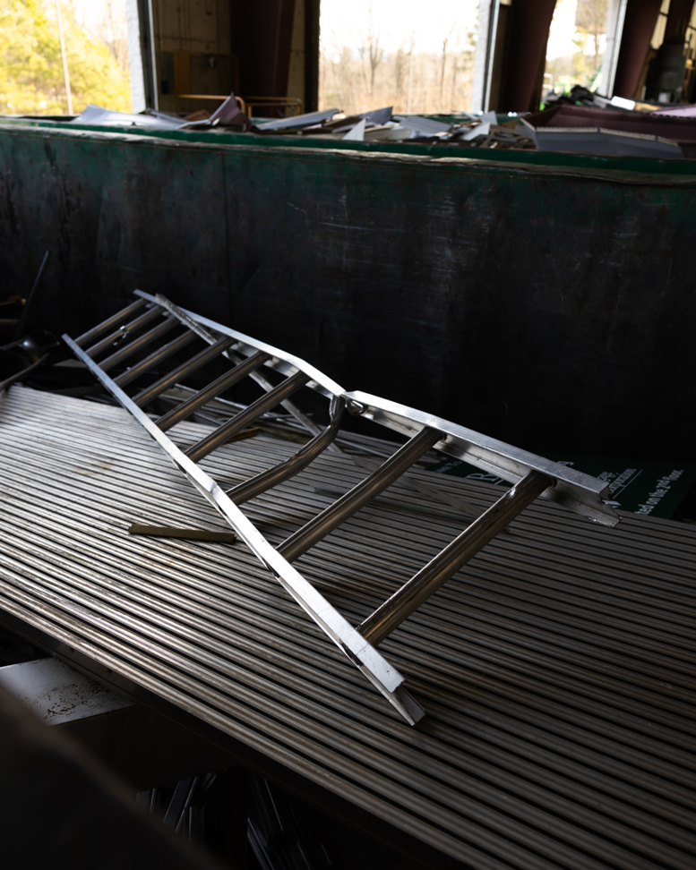 A metal ladder and other scrap items inside a large green dumpster at Bee Green Recycling in Richmond, VA