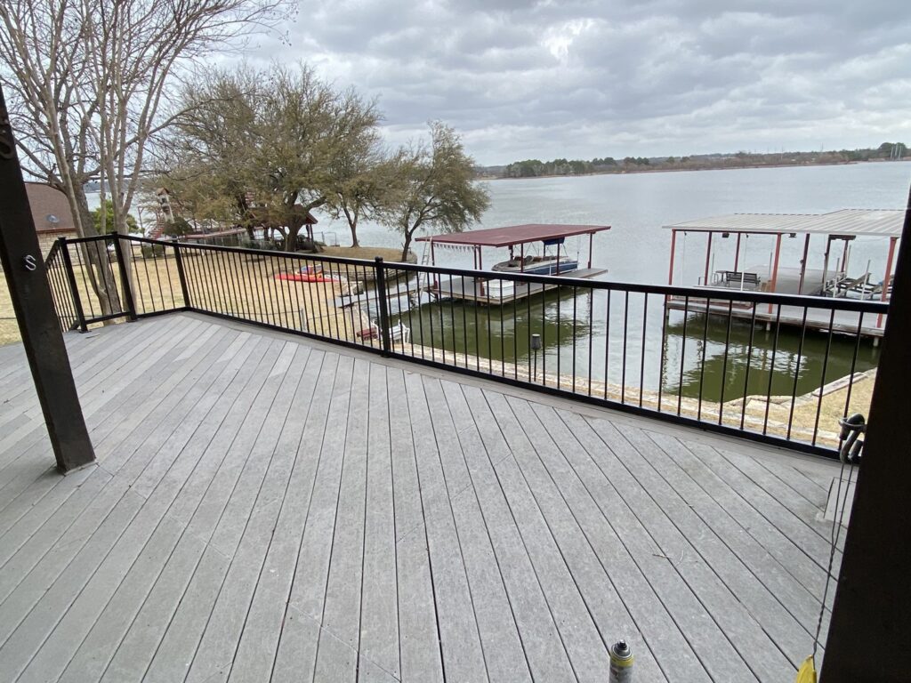 A newly installed lakefront deck with black metal railings, offering scenic views, completed by Falls Contracting, LLC in Raleigh, NC.