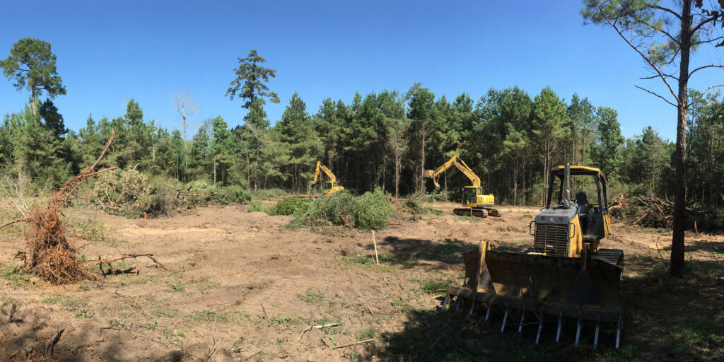 Multiple excavators actively clearing land for a project by Daniel Dean Land Clearing & Dirt Work in Houston, TX.