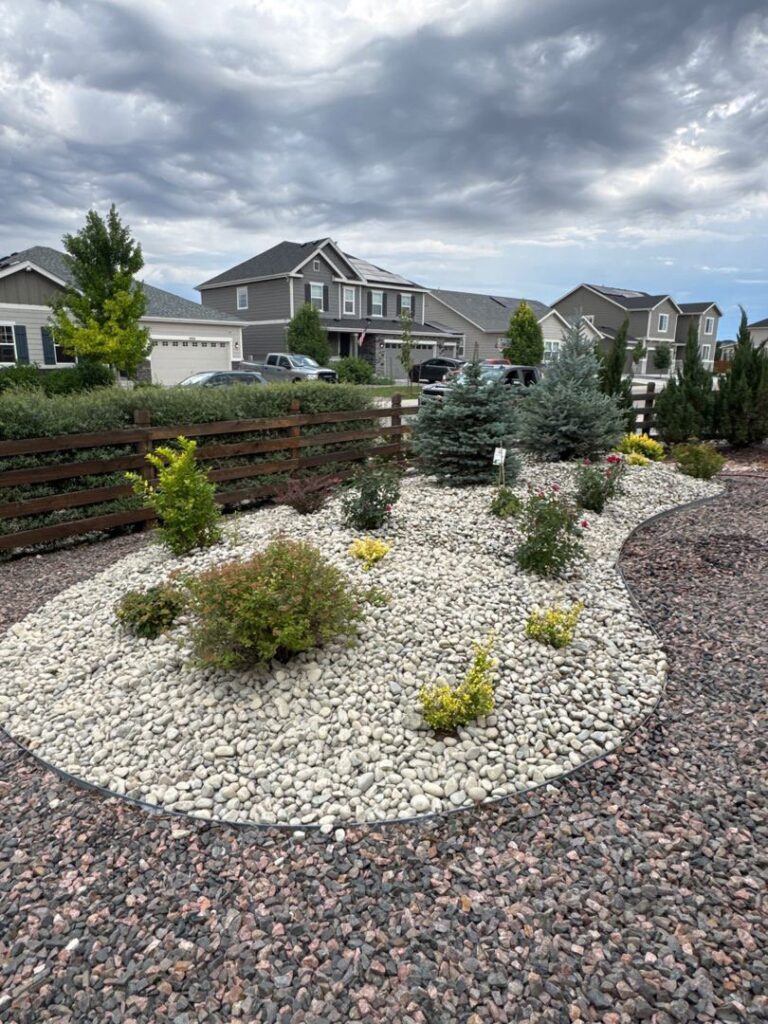A beautifully landscaped garden bed with gravel and various plants designed by Blue Collar Service Pros in Aurora, CO.