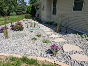 A beautifully landscaped area featuring decorative gravel, stepping stones, and various plants by Wildflower Landscapers LLC in Larsen, WI