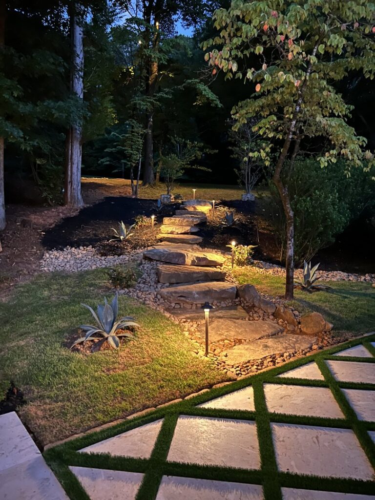 A beautifully landscaped stone staircase with integrated pathway lighting, a hardscaping project by Picasso Poolscapes in Johns Creek, GA.